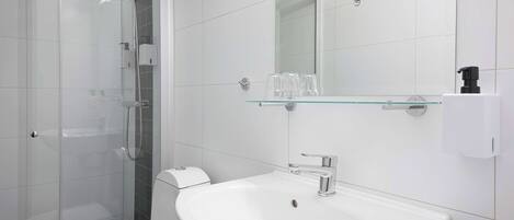 A modern bathroom with a glass shower enclosure, a white sink, and a mirror above the sink.