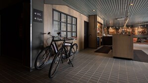 A modern interior with a bike rack, a reception desk, and directional signs for WC and Gym.