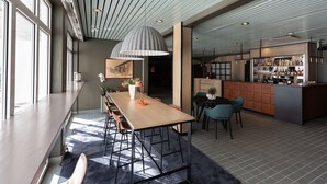 A modern kitchen with a bar area, large windows, and a dining area with a long table and chairs.