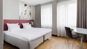 Ett hotellrum med en stor säng, ett skrivbord och en stol.