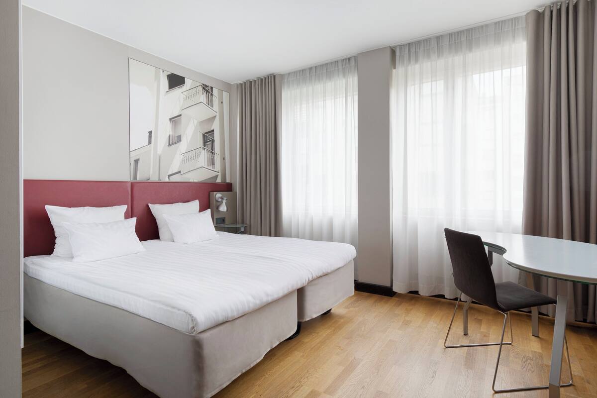 A hotel room with a large bed, a desk, and a chair.
