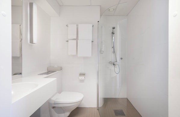 Un baño moderno con inodoro, lavamanos y ducha.
