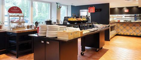 A breakfast buffet area with a variety of food items, a coffee station, and a counter with a patterned backsplash.