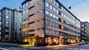 Ett hotell med flera våningar, en fasad av tegel, stora fönster och en restaurang på markplan.