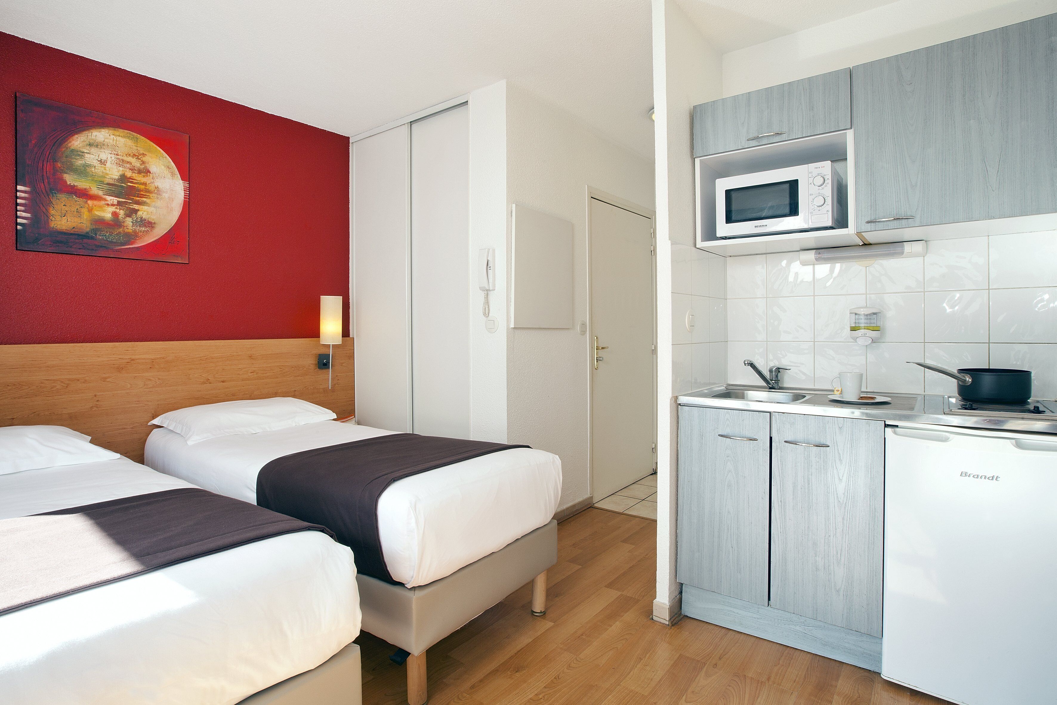 A hotel room with two beds, a microwave, a sink, and a cabinet.