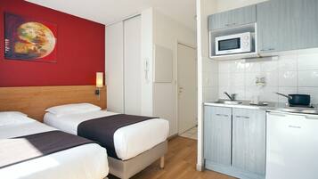 A hotel room with two beds, a microwave, a sink, and a cabinet.