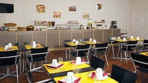 Un comedor con mesas dispuestas para el desayuno, incluyendo cafeteras y un bufé con diversas opciones de comida.