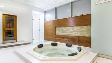 A modern bathroom with a large bathtub, a wooden panel wall, and a tiled floor.