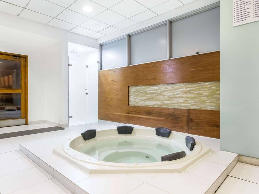 A modern bathroom with a large bathtub, a wooden panel wall, and a tiled floor.