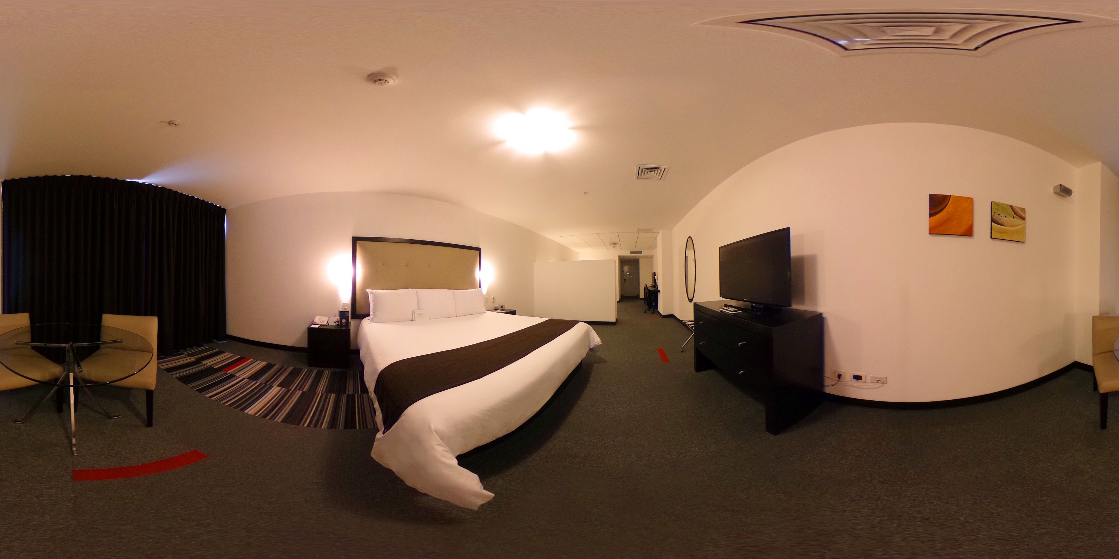 Una habitación de hotel con cama, televisión, escritorio y silla.