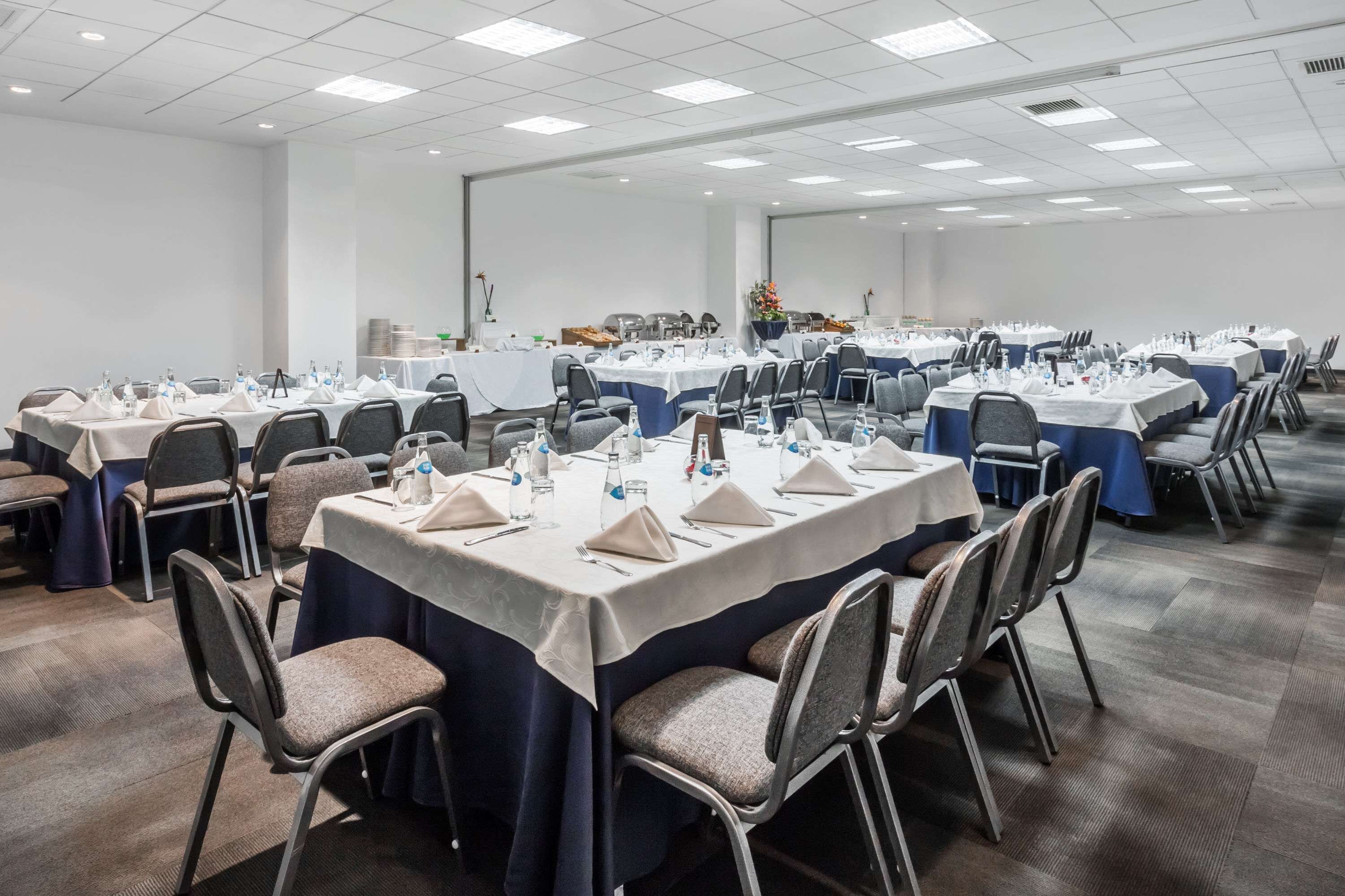A conference room with multiple tables set for meetings, equipped with chairs, water bottles, and nameplates.