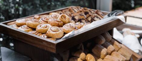A tray of assorted pastries including cinnamon rolls and sesame seed buns.