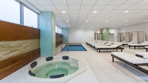 Un área de spa con un jacuzzi, sillones reclinables y una piscina.