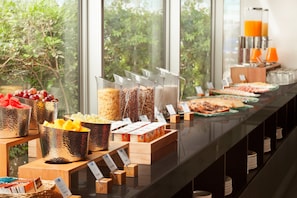 Buffet com diversas opções de comida e vista para o verde lá fora.