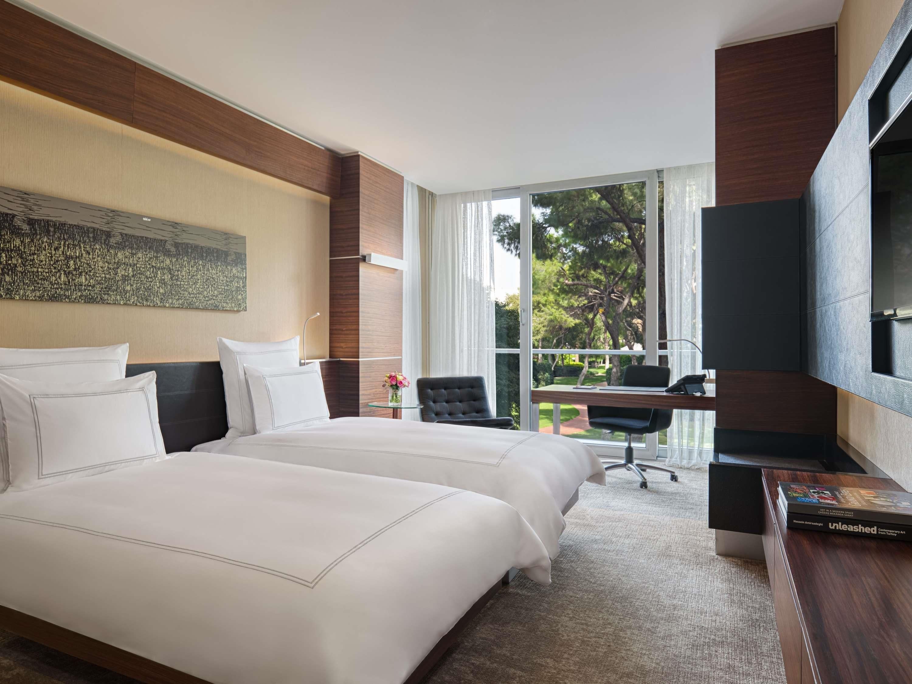 A hotel room with a large bed, a desk, a chair, and a television.