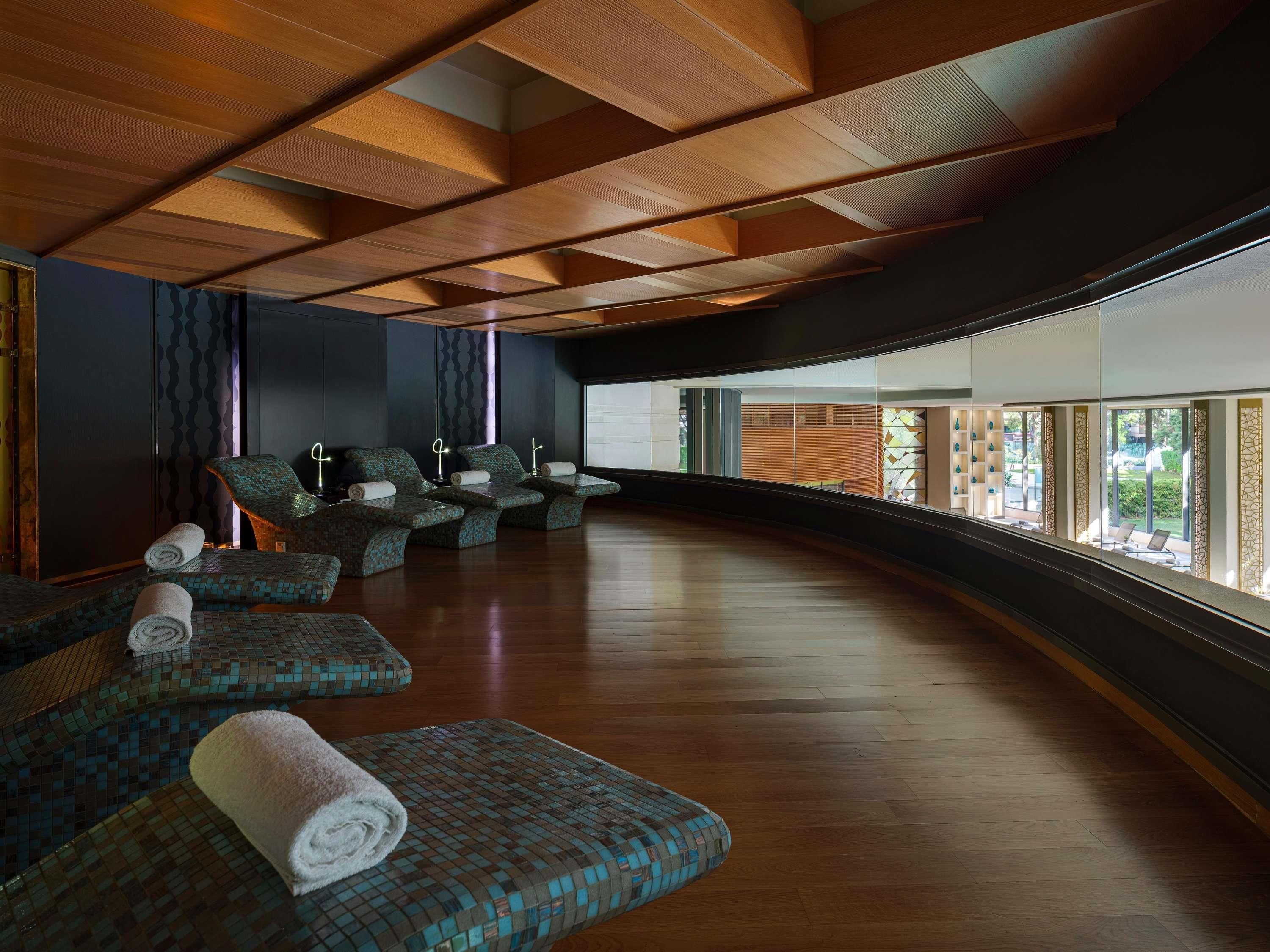 Un espace spa moderne doté d’un plancher en bois, de sièges aux motifs originaux et offrant une vue sur l’extérieur.