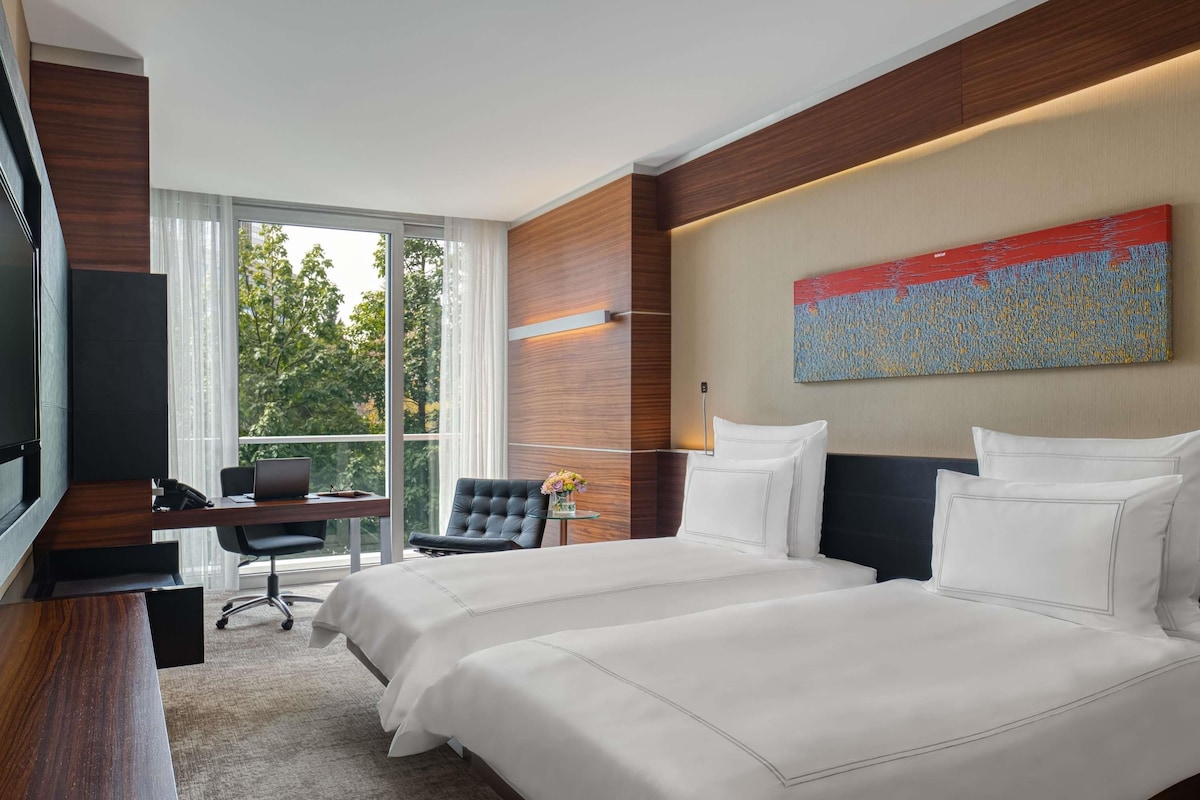 Une chambre d’hôtel avec un grand lit, un bureau, une chaise et un téléviseur.