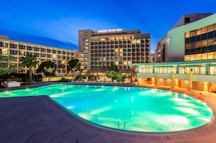 Un hotel con piscina, varias plantas y fachada bien iluminada.