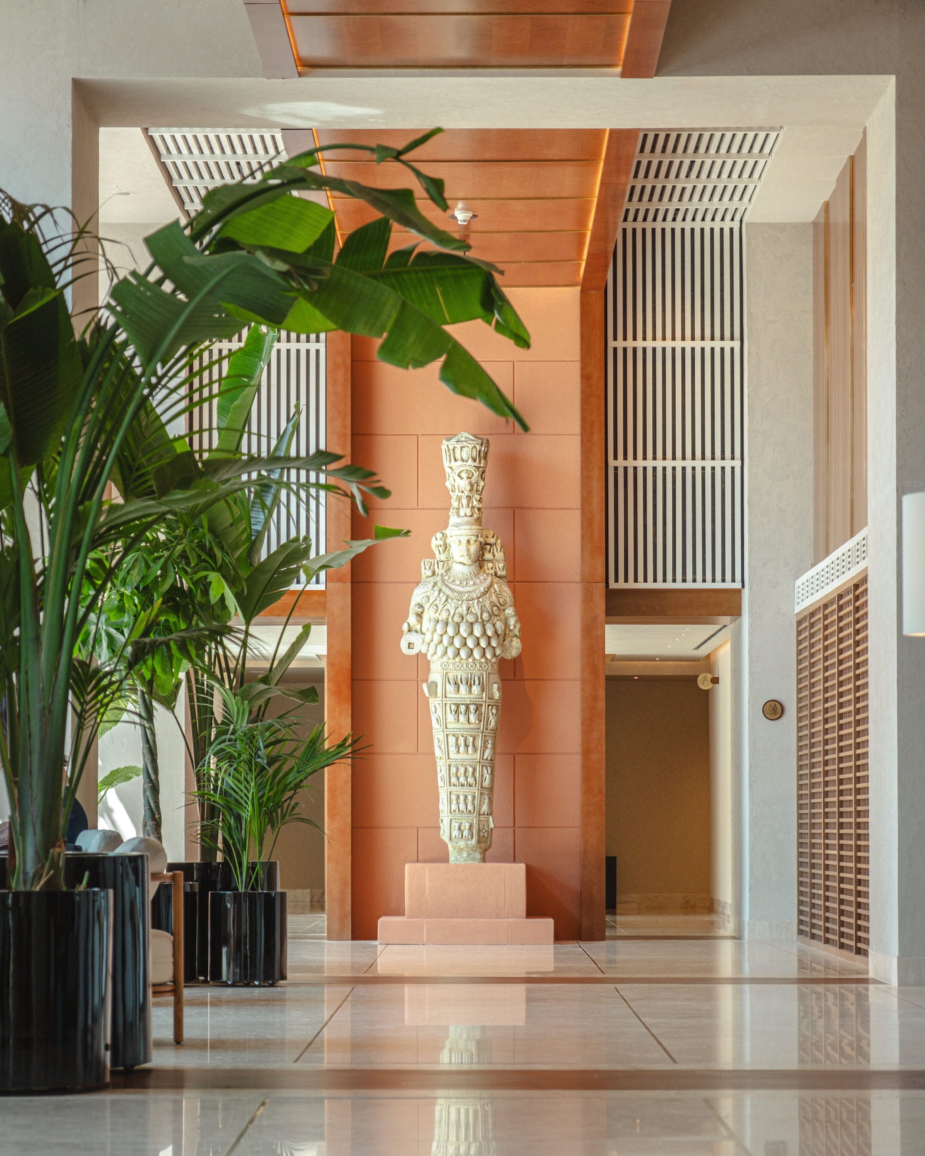 Eine moderne Lobby mit einer zentralen Skulptur, Topfpflanzen und einem sauberen, polierten Boden.