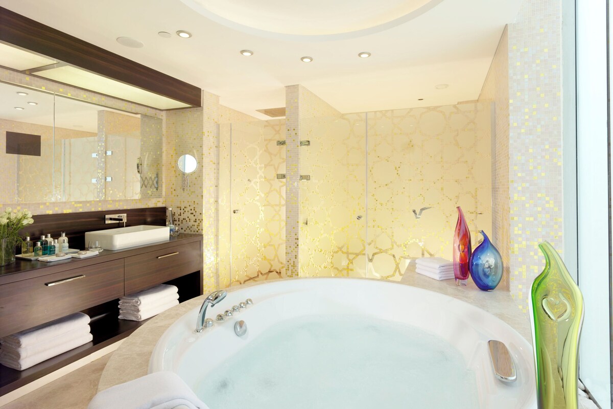 A modern bathroom with a large bathtub, a vanity with a mirror, and a shower area.