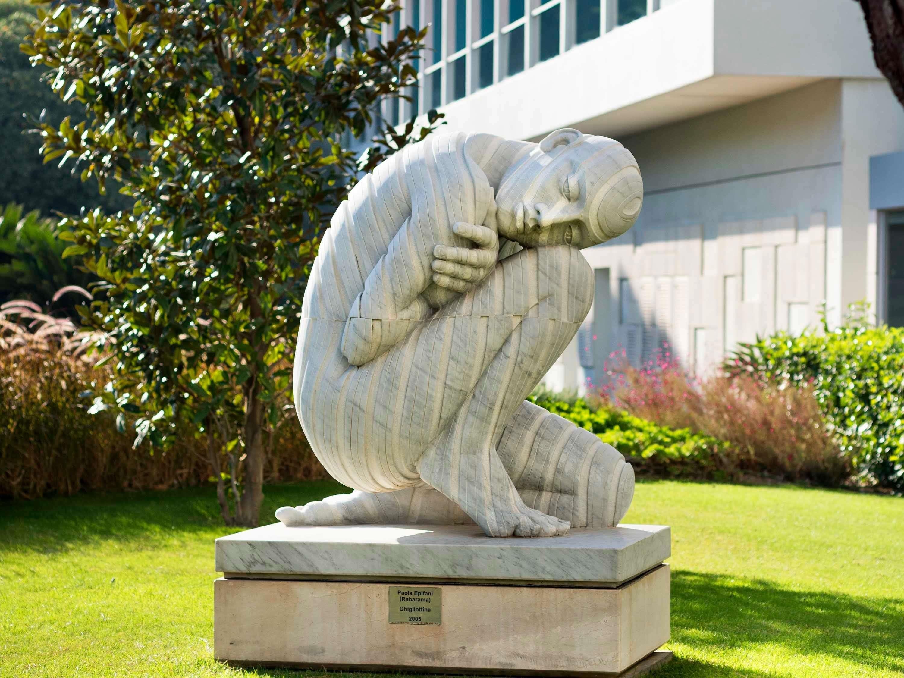A sculpture of a person in a contemplative pose, set on a pedestal with a plaque.