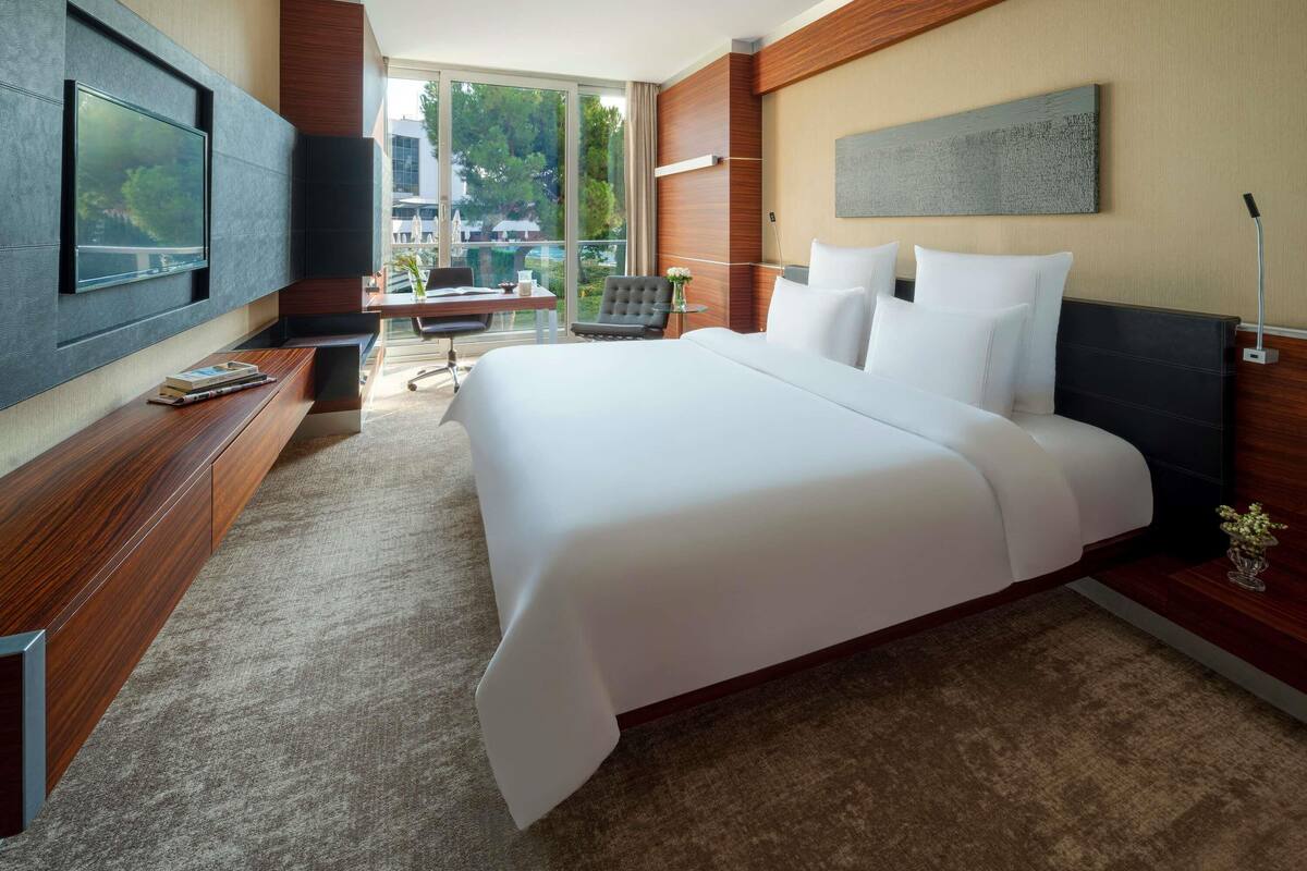 Une chambre d’hôtel moderne dotée d’un grand lit, d’une télévision à écran plat, d’un bureau et offrant une vue sur l’extérieur.