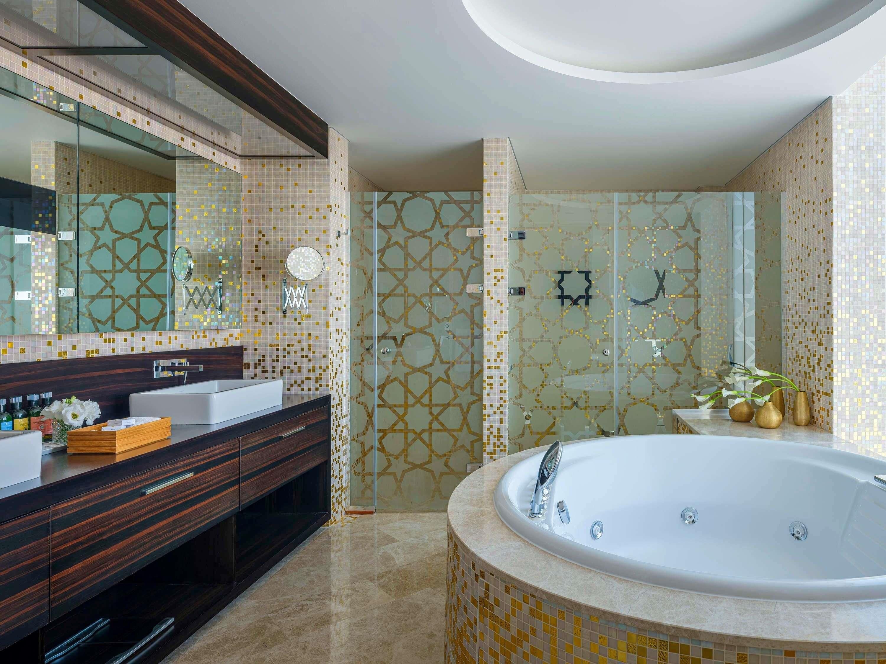 A modern bathroom with a large bathtub, dual sinks, and a glass shower enclosure.