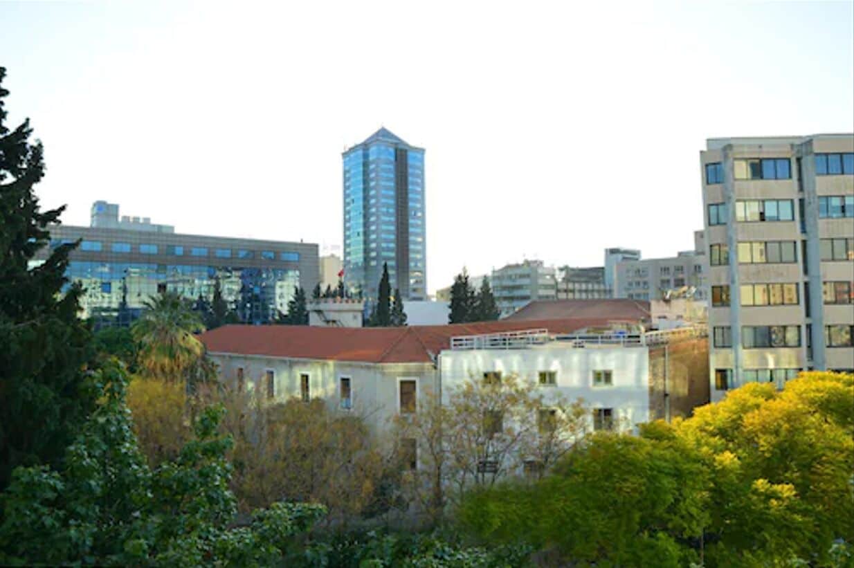 A cityscape with modern buildings, including a tall skyscraper and several mid-rise structures.