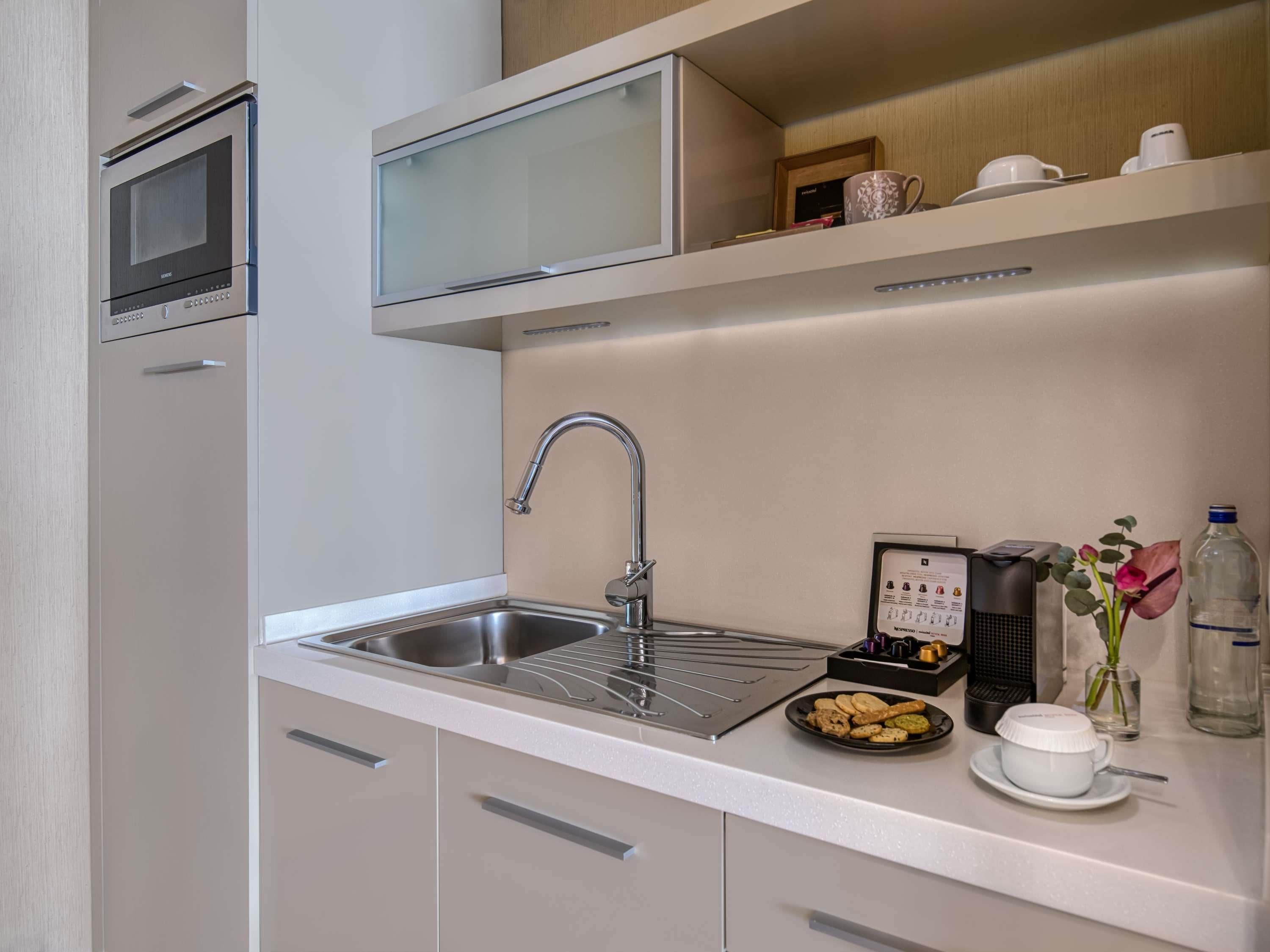 Cocina moderna con un lavamanos de acero inoxidable, un microondas y una cafetera.