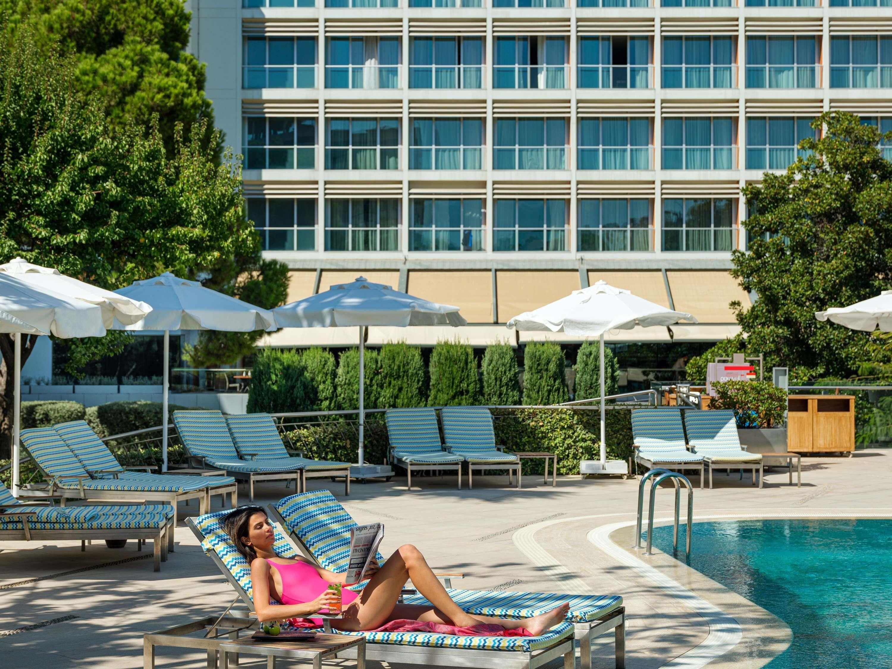 A poolside area with lounge chairs, umbrellas, and a building in the background.