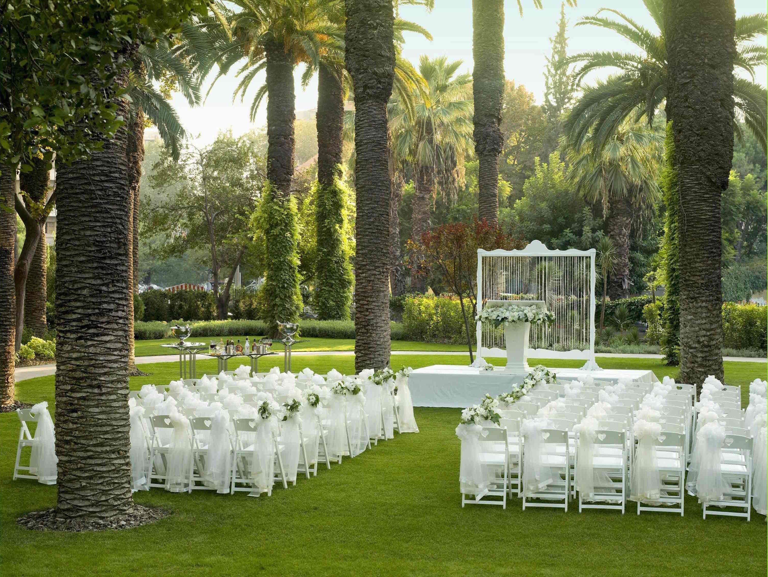 Decoración para una ceremonia de boda con sillas blancas y un arreglo floral.