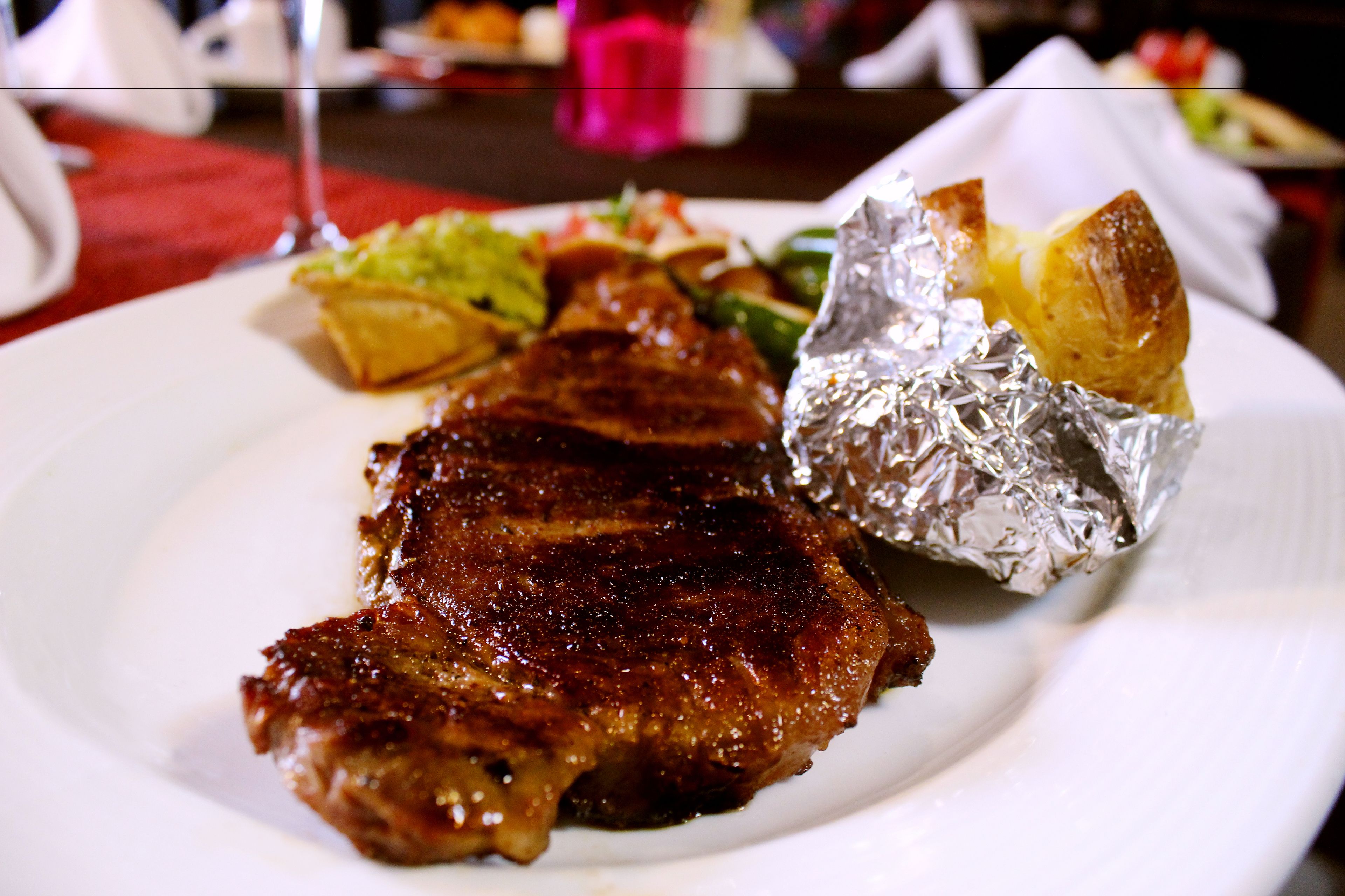 Un plato con un filete a la parrilla, patatas asadas y una ensalada.