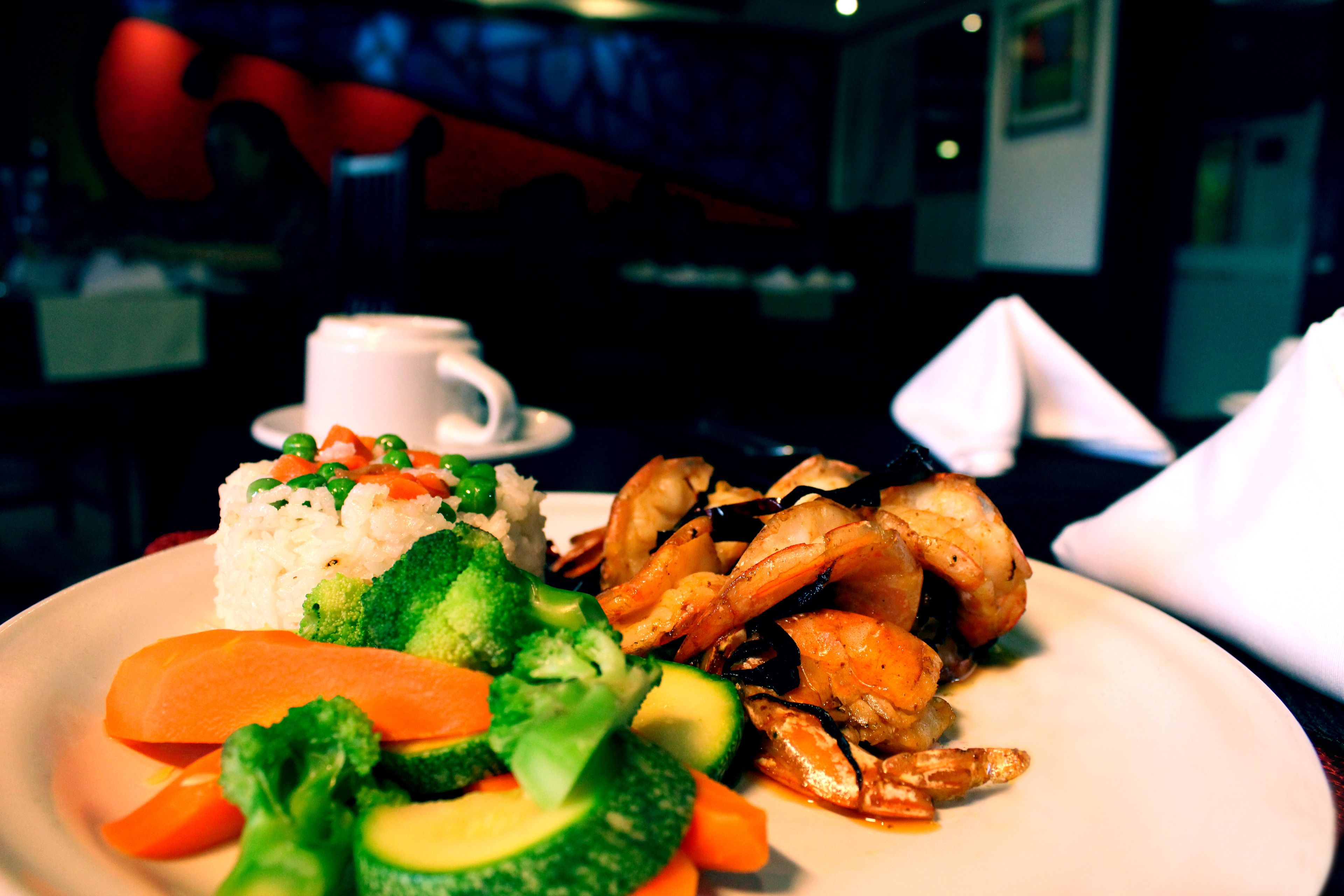 A plate of food with rice, vegetables, and shrimp.