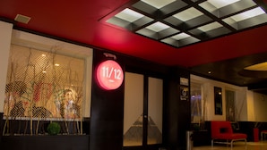 A modern interior with a geometric wall design, a red sign indicating a bar, and a red chair. - Mia City Villahermosa (Villahermosa)