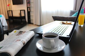 A laptop on a table with a cup of coffee and a newspaper.