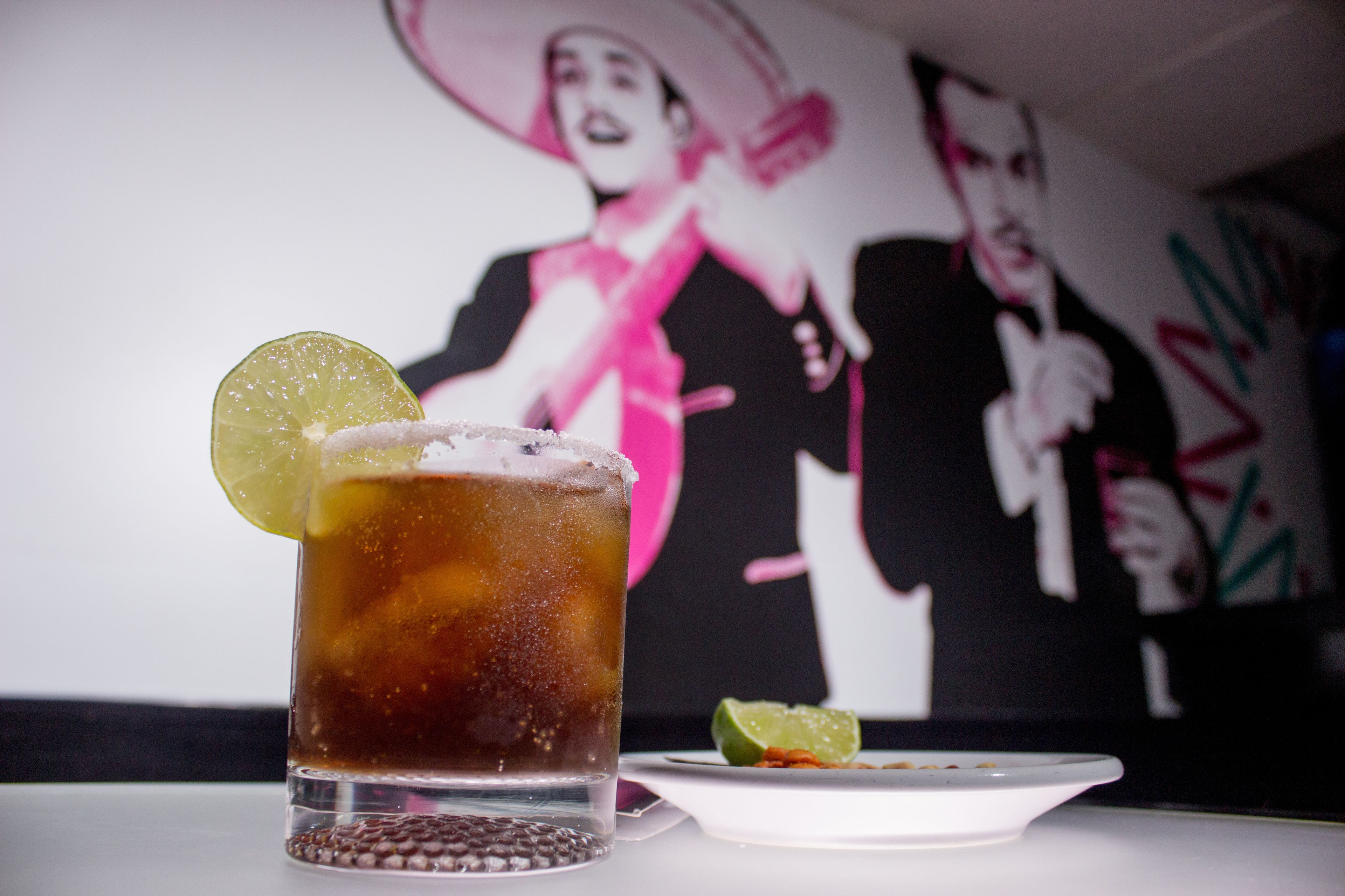 A glass of iced tea with a lime slice garnish on a white table.