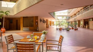 A spacious indoor area with a dining table set for breakfast, surrounded by chairs, and a balcony with potted plants. - Best Western Plus Plaza Florida & Tower (Irapuato)