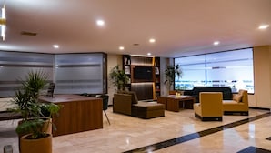 A modern lobby with a reception desk, seating area, and large windows offering a view of the outside. - Best Western Plus Plaza Florida & Tower (Irapuato)