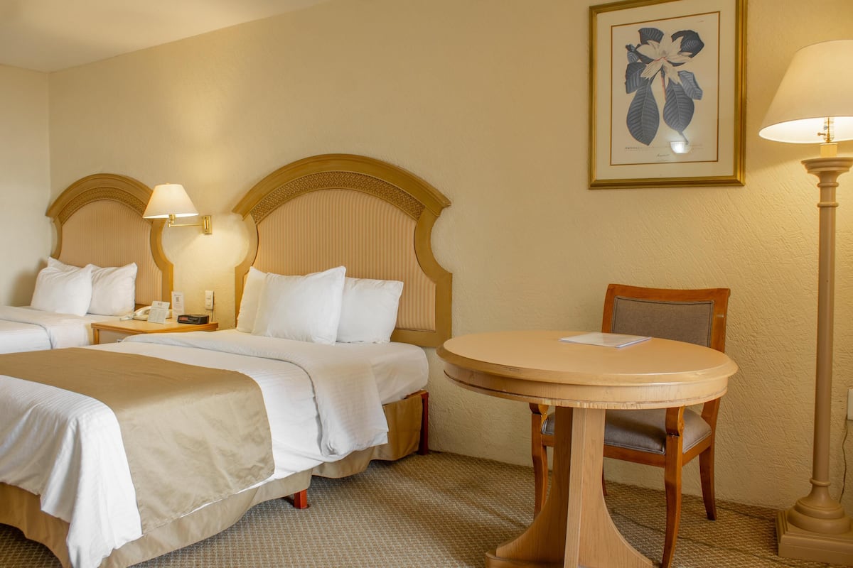 Une chambre d’hôtel avec deux lits, une table ronde et une chaise.