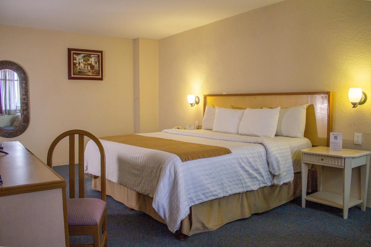 Une chambre d’hôtel comprenant un lit, une table de chevet, une chaise et un bureau.
