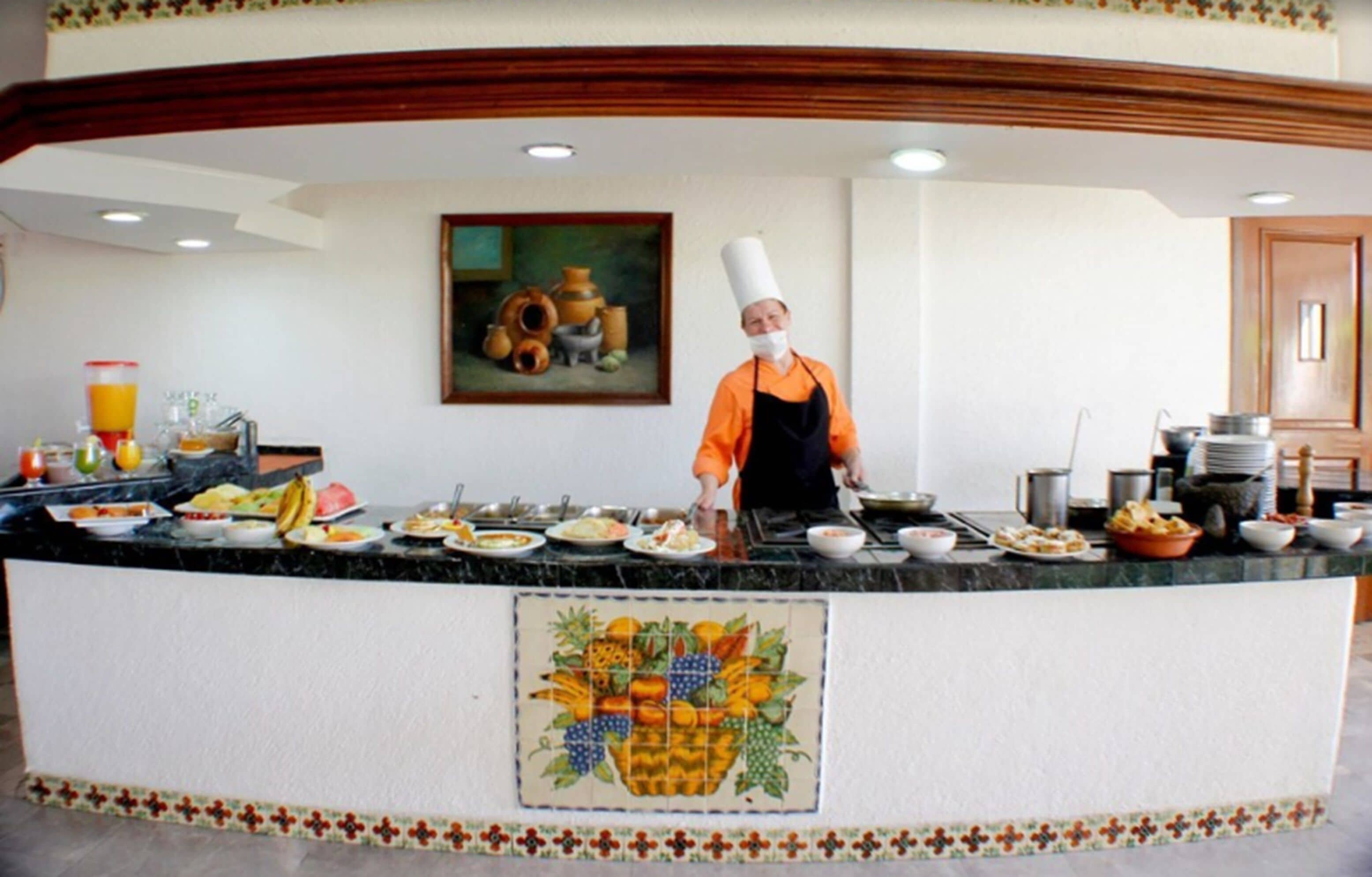 Ein reichhaltiges Buffet mit Koch in orangefarbener Uniform und Kochmütze.