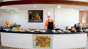 A buffet setup with a chef in an orange uniform and white chef's hat.