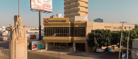 Un edificio con un letrero de 'Best Western PLUS', una estatua y un cartel publicitario.
