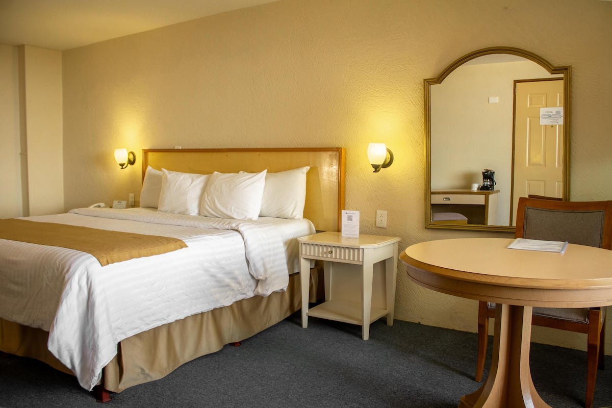 Une chambre d’hôtel comprenant un lit, une table de chevet, une table ronde et un miroir.