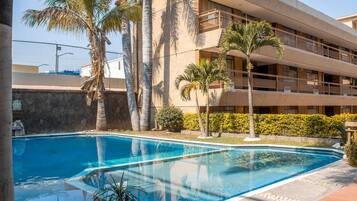 Una piscina al aire libre, sillones reclinables de piscina