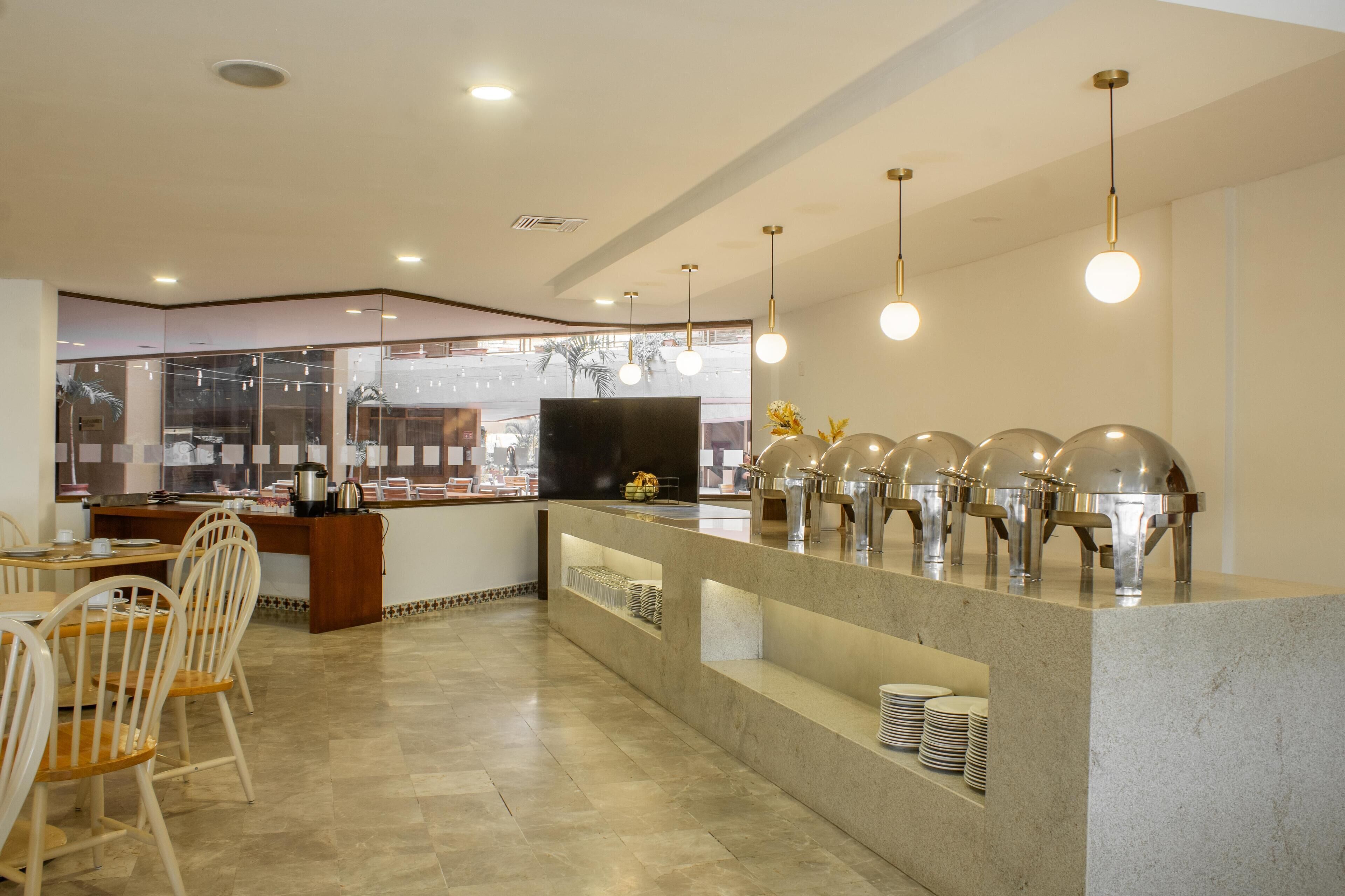 A modern restaurant with a buffet setup, including a counter with food dispensers and a seating area with chairs and tables.