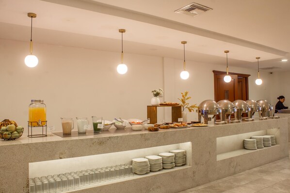 A buffet setup with a variety of food items, a beverage station, and a counter with stacked plates.
