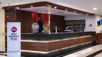 Una recepción con el letrero de Best Western PLUS, un jarrón con detalles decorativos y un monitor en la pared.