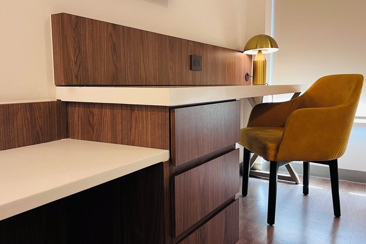 Una habitación moderna con una pared de acento de madera, un escritorio blanco, una silla amarilla y una lámpara.