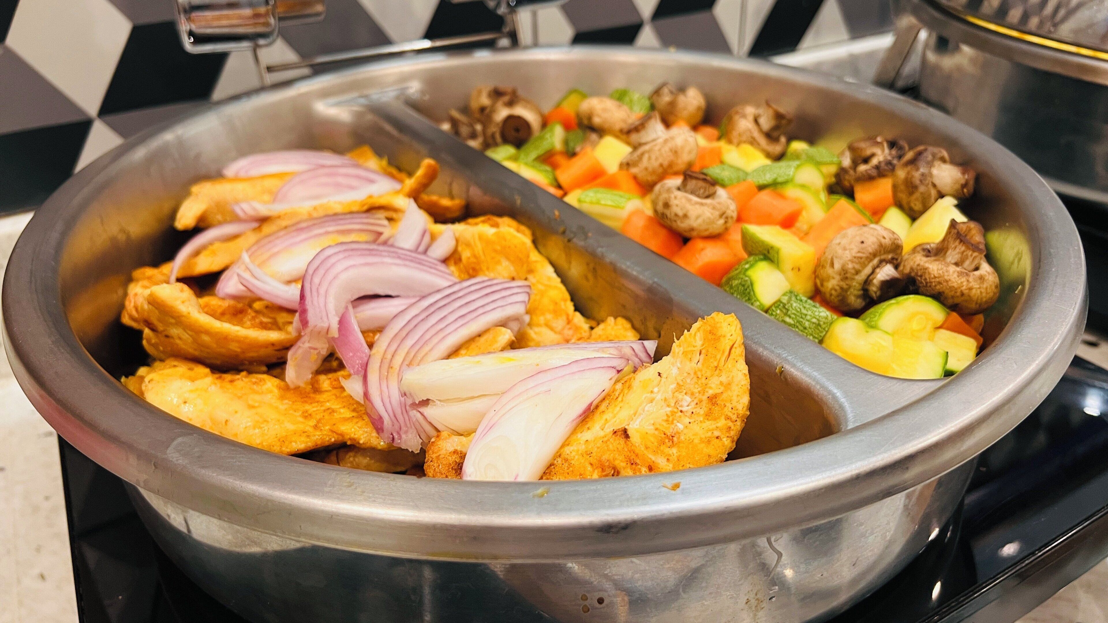 A buffet with various food items including fried chicken, vegetables, and mushrooms.